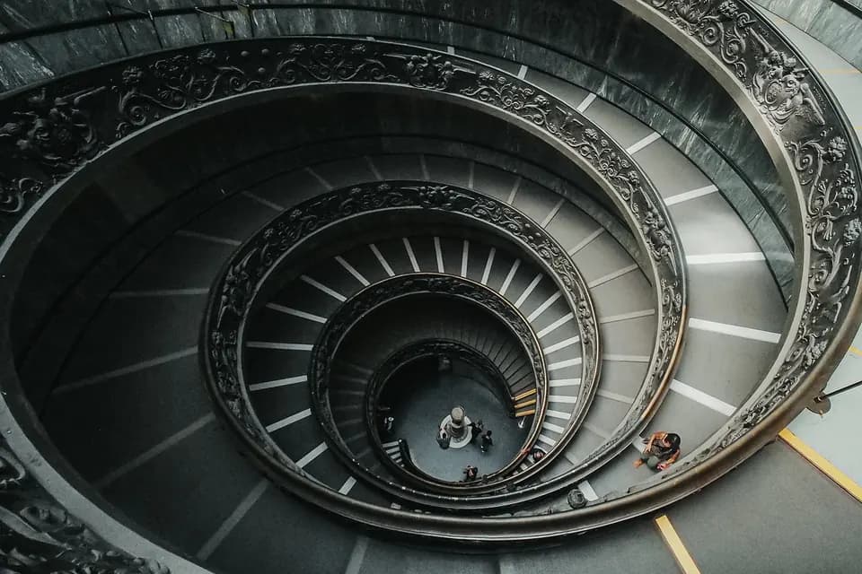 A spiral staircase photographed from above, its steps winding in an even, ordered curve.