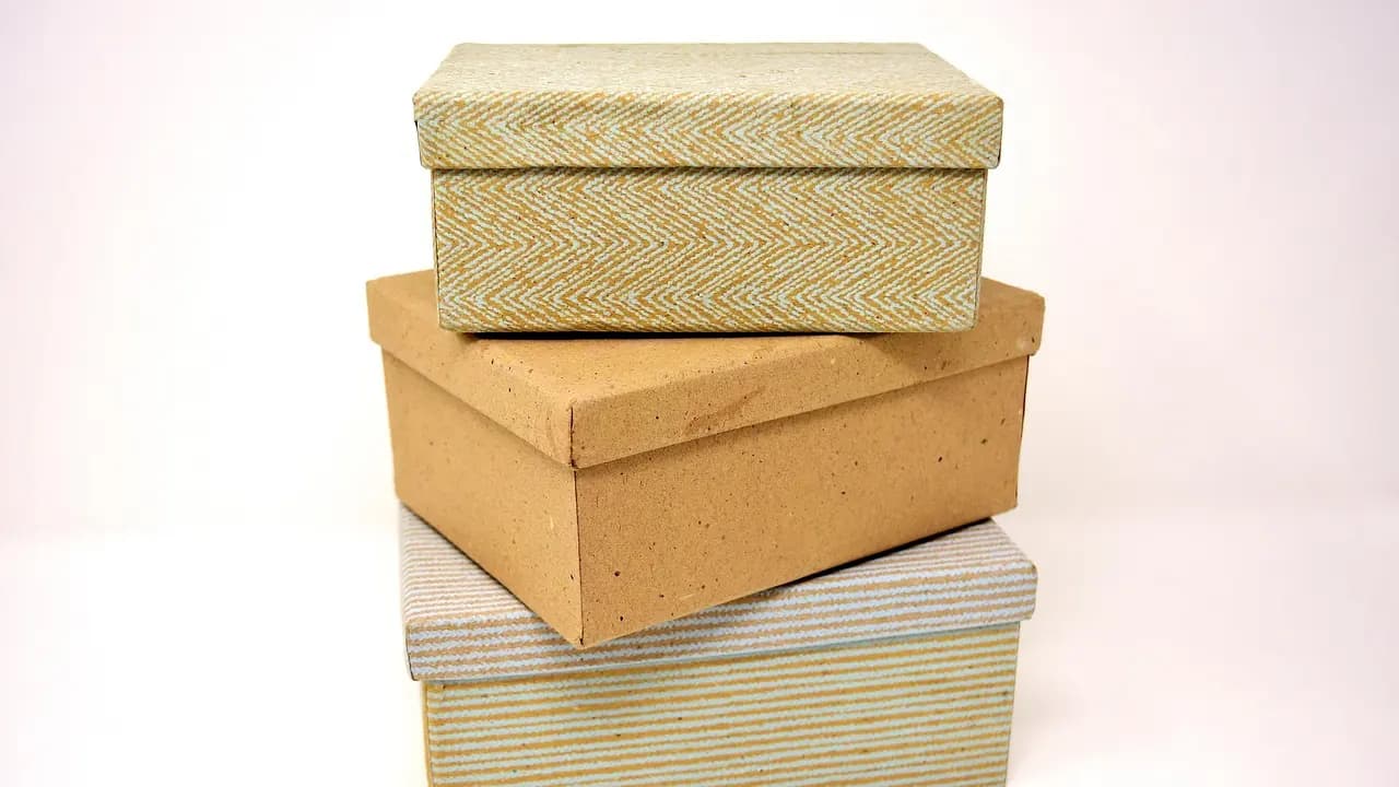 Plain cardboard shipping cartons stacked against a pale background.