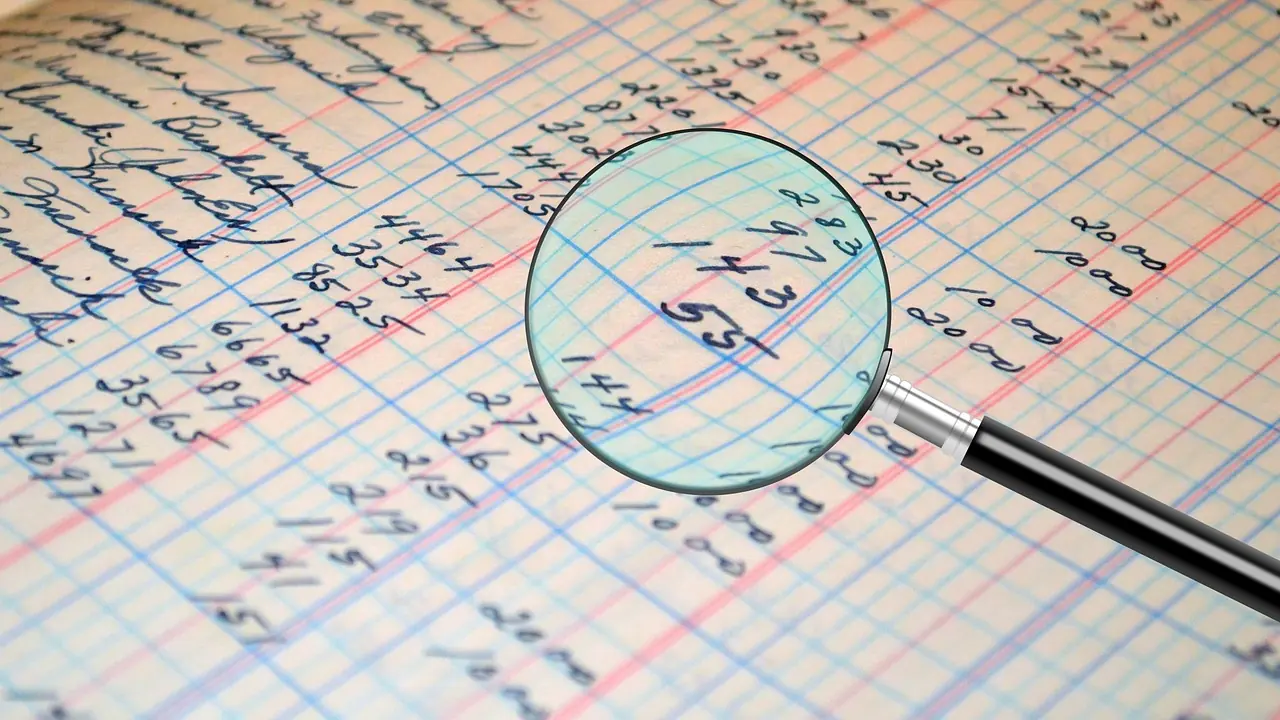 A magnifying glass held over a column of handwritten figures in a ledger.