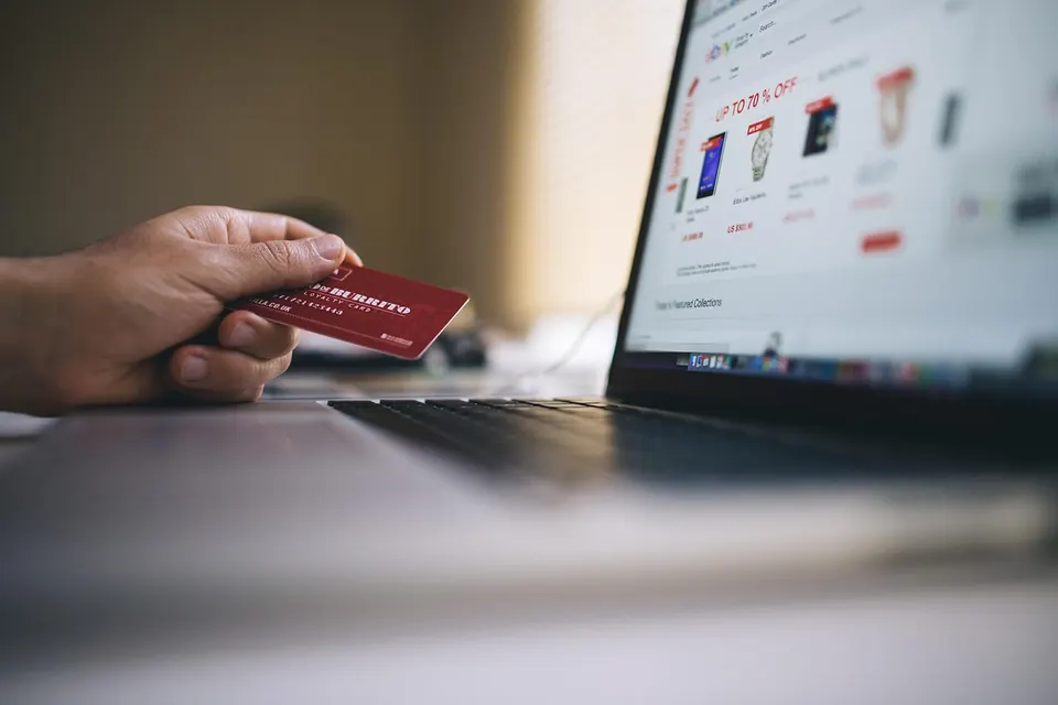 A laptop showing an online storefront, a payment card resting beside it.
