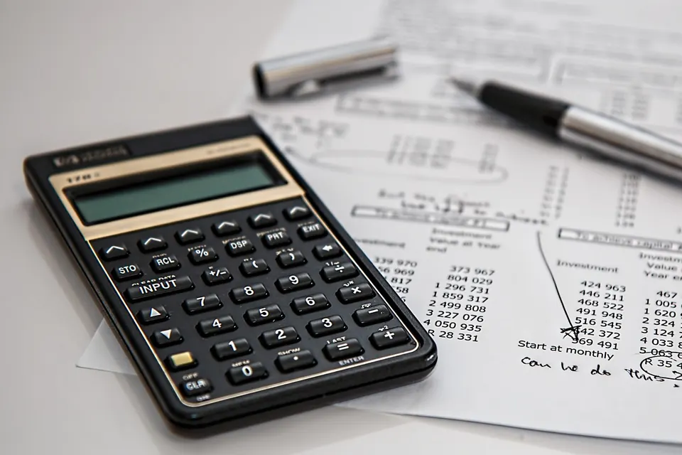 A desk calculator resting on printed spreadsheets of tax figures.